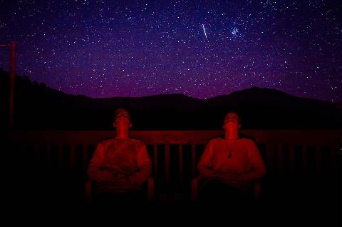 Two people looking upward at a sky full of stars.