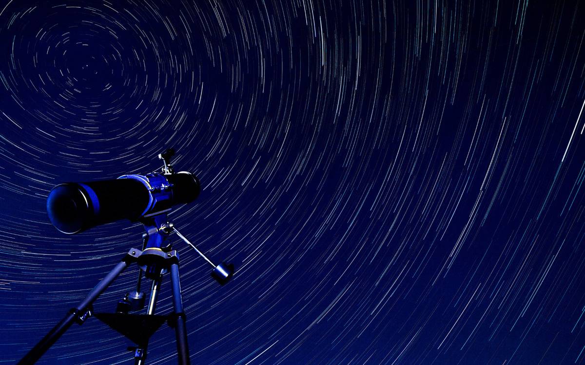 A spinning sky of stars with a telescope looking at them.
