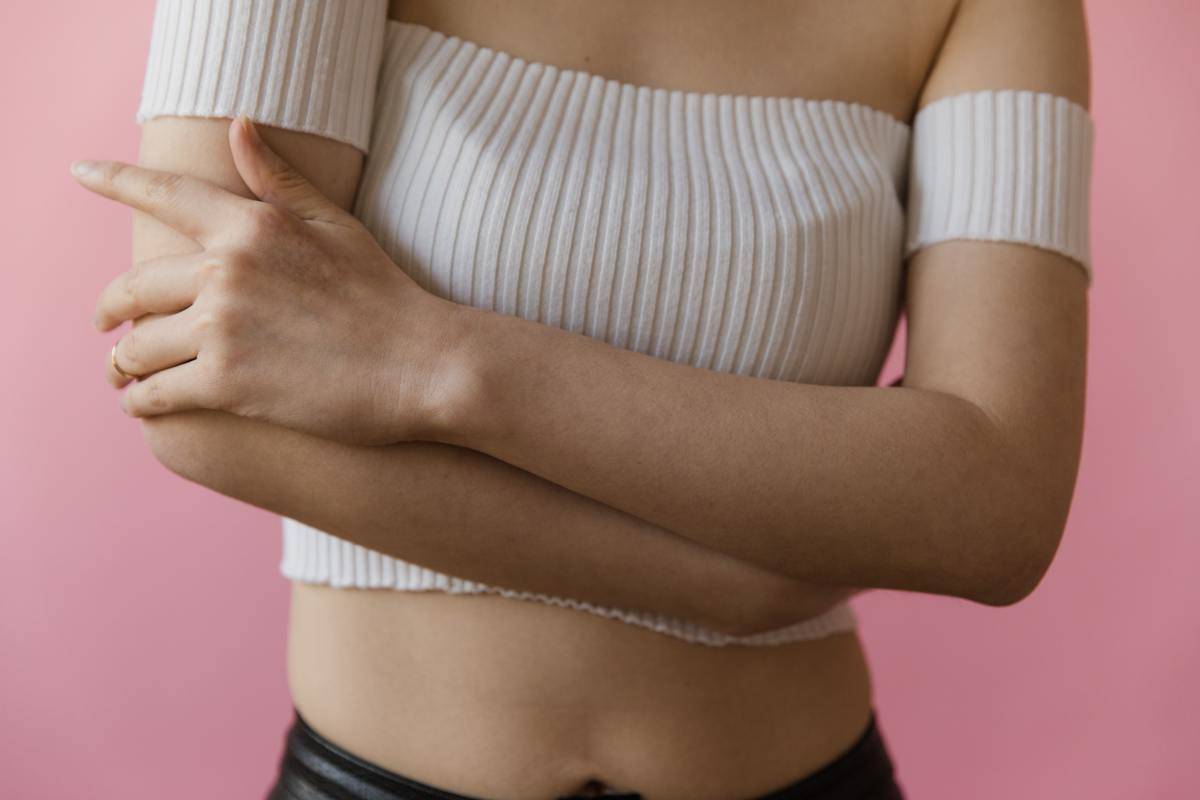 A woman crossing her arms in front of her chest.