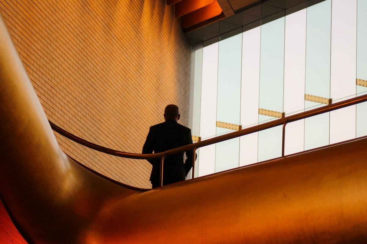 A man standing atop a balcony in an office building.