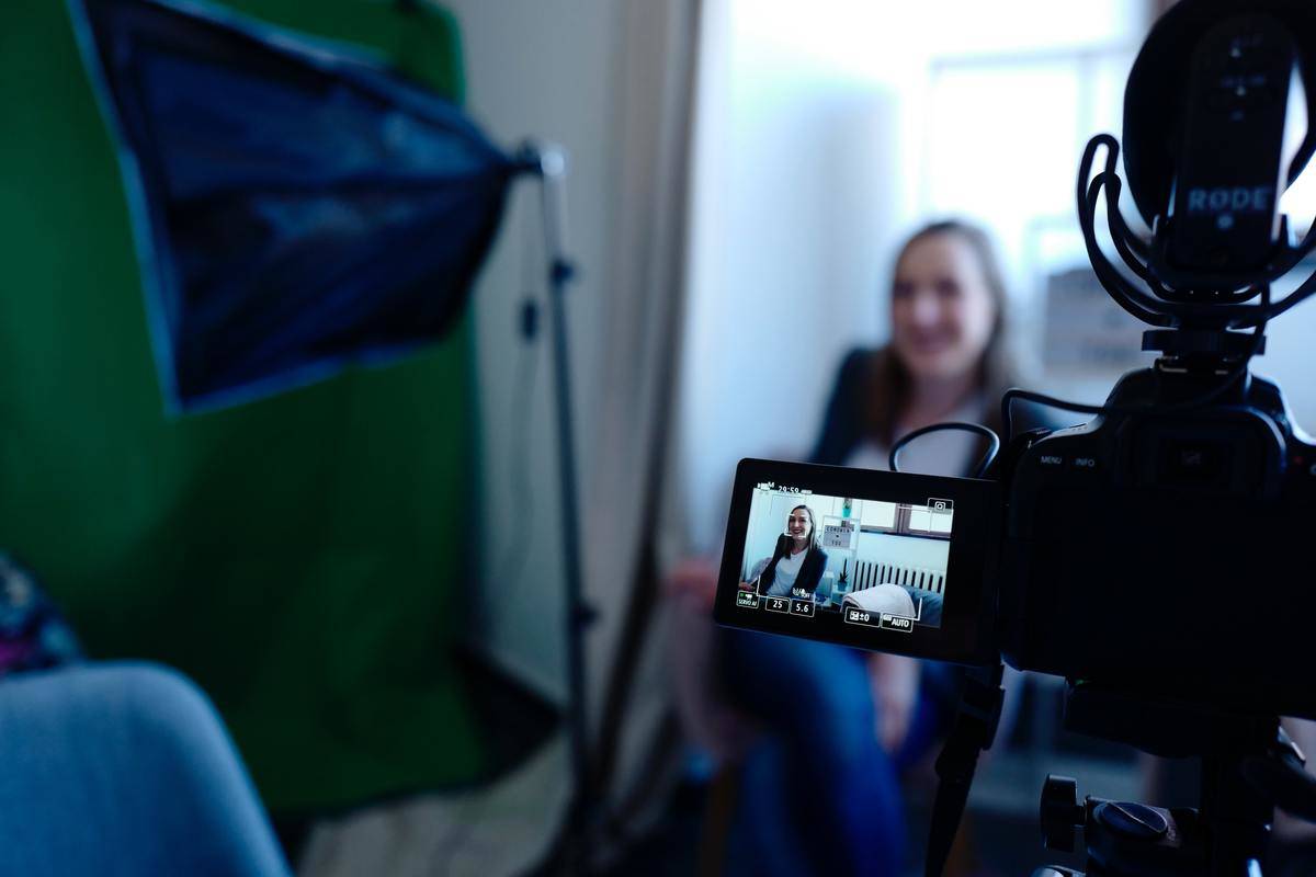 A woman sitting in front of a camera, seen through the camera's screen.