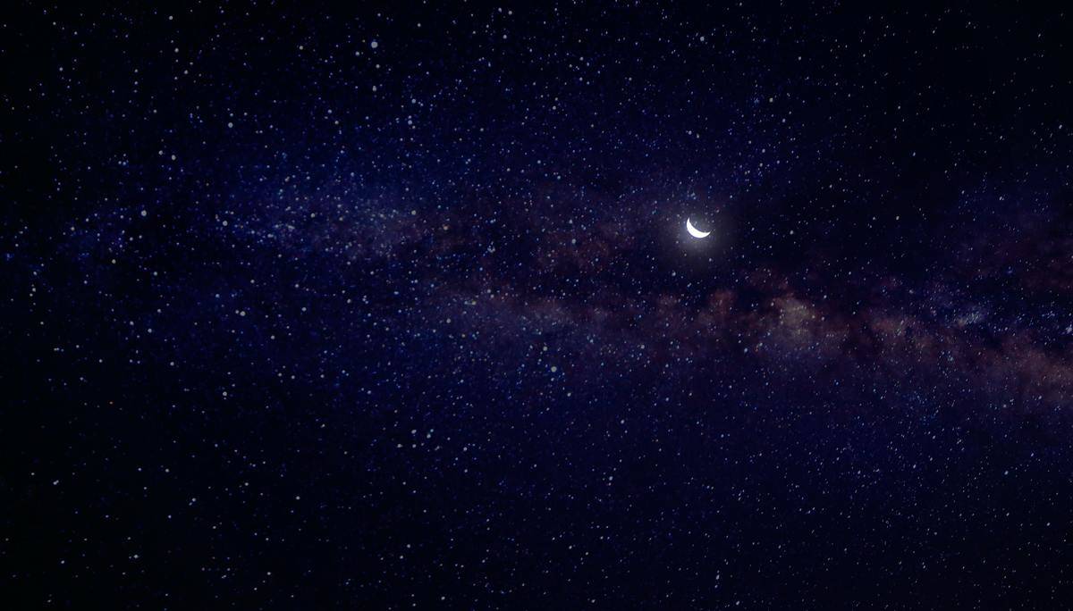 A night sky full of stars, a crescent moon visible.