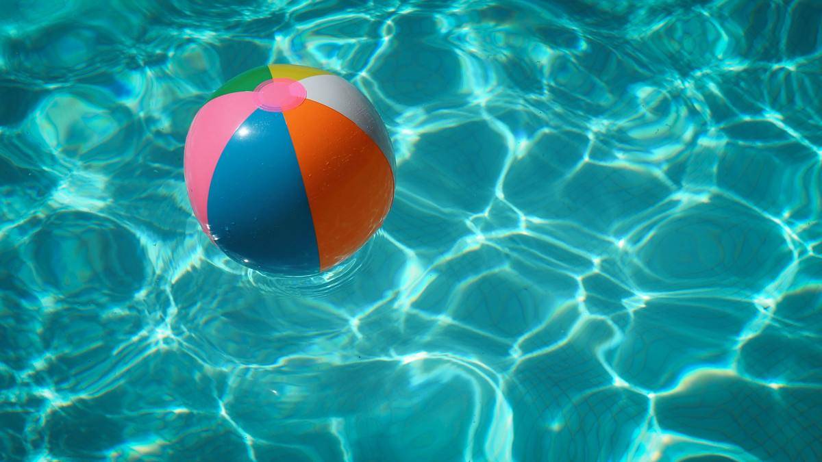 A beach ball in the water of a pool.