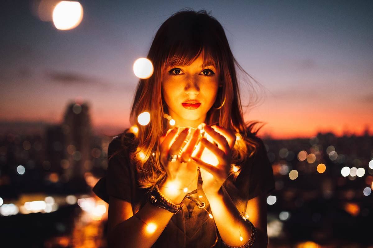 A woman holding a bundle of string lights.