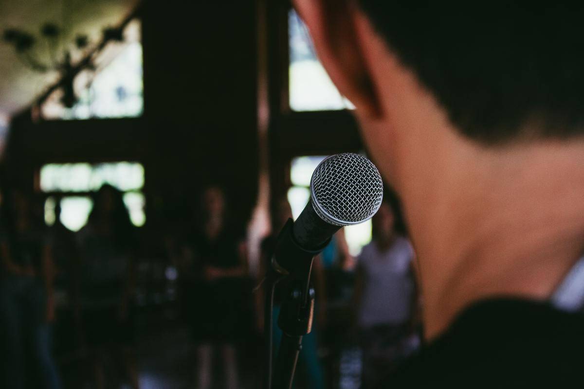 A man with a mic before a crowd.