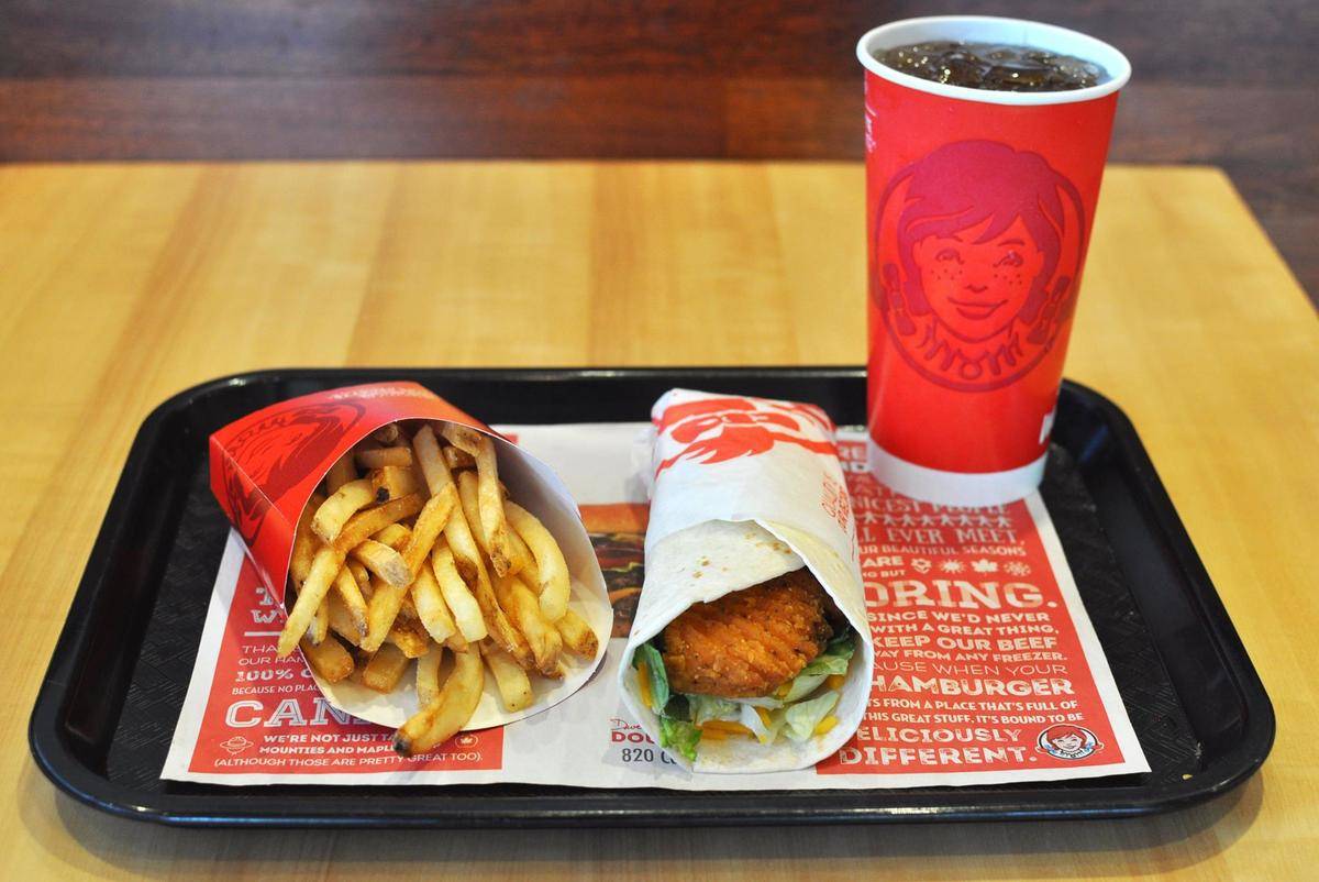 A Wendy's wrap, serving of fries, and fountain drink on a tray.