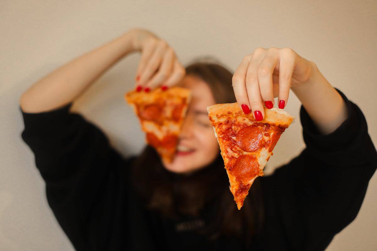 woman-holding-sliced-pizza-with-pepperoni-