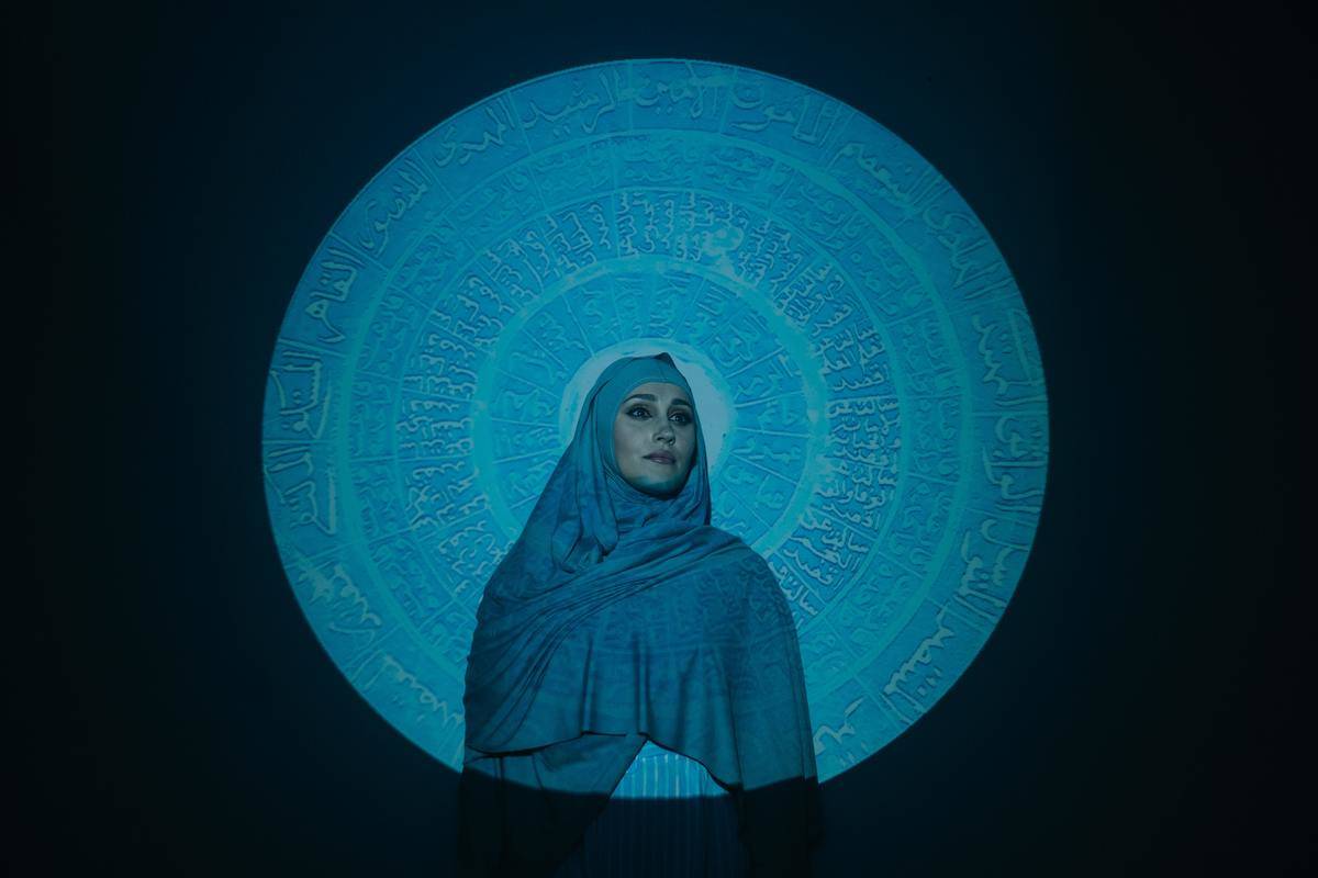 woman-in-blue-hijab-standing-beside-blue-and-white-wall-