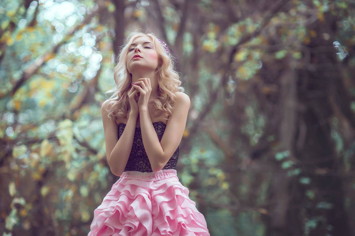 woman praying in forest standing in big pink skirt