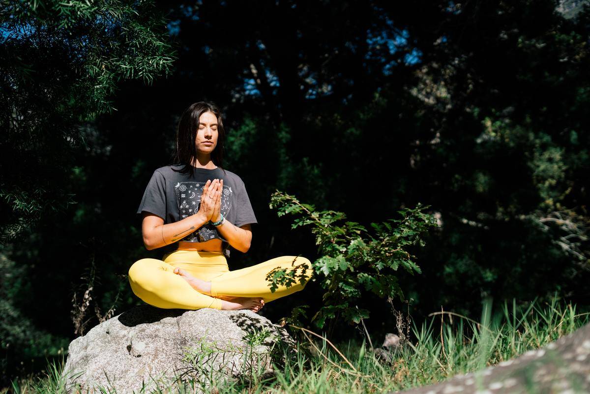 photo-of-woman-doing-yoga-while-sitting-on-rock