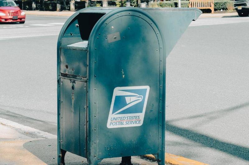a-blue-metal-mail-box-on-the-side-of-the-road-