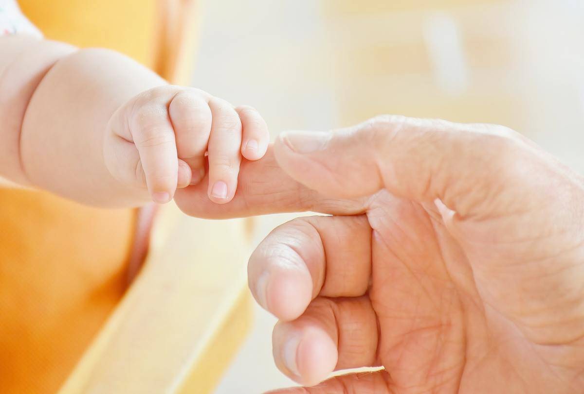 adult hand holding baby's fingers