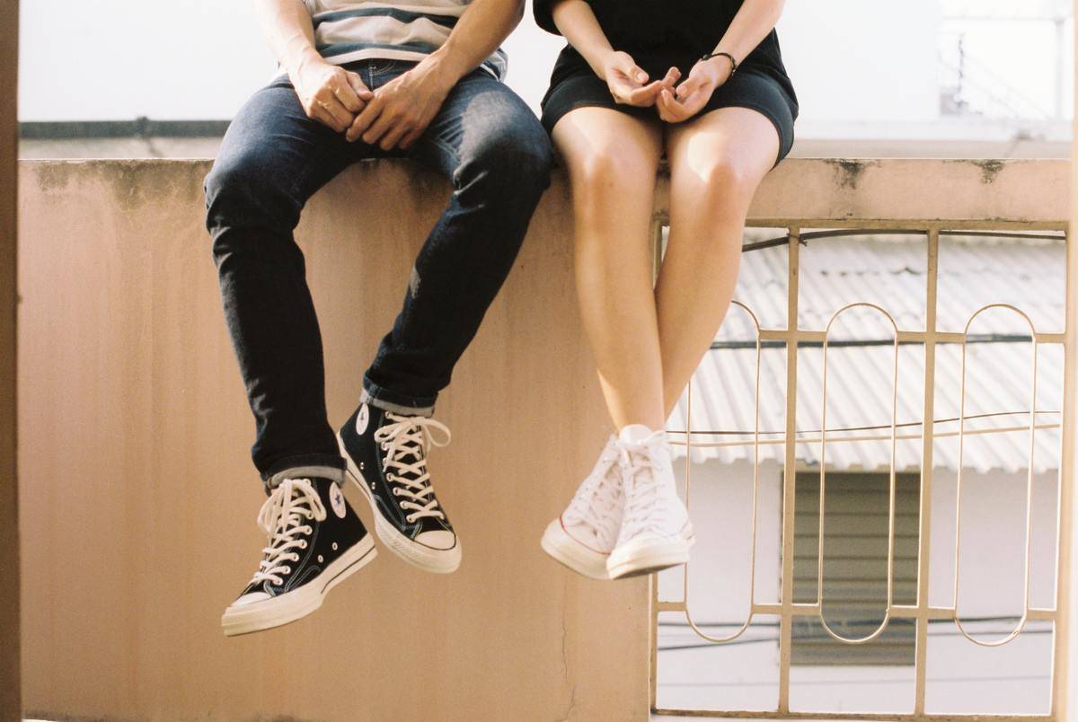 Two people sitting on a wall, the shot just showing their legs hanging over the edge.
