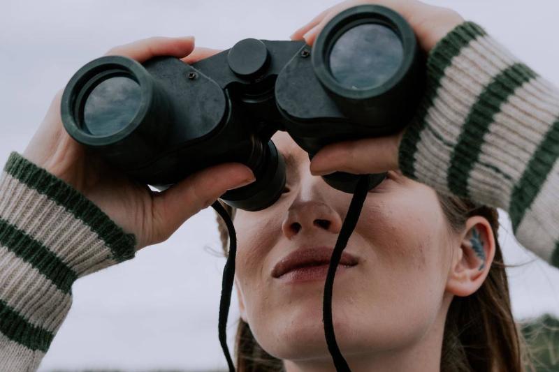 woman looking through a pair of binoculars.