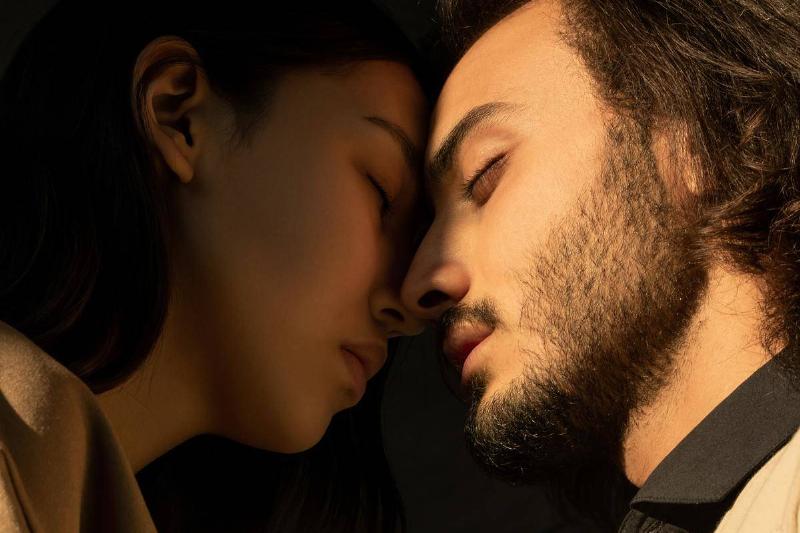 close-up-photo-of-couple-with-their-eyes-closed-facing-each-other-in-front-of-dark-background