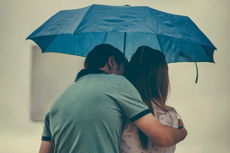 man-hugging-woman-while-holding-umbrella
