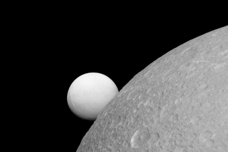 Enceladus floating behind another one of Saturn's moons, Dione.