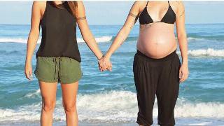 Melanie and Vanessa holding hands on the beach, showcasing Melanies pregnancy.
