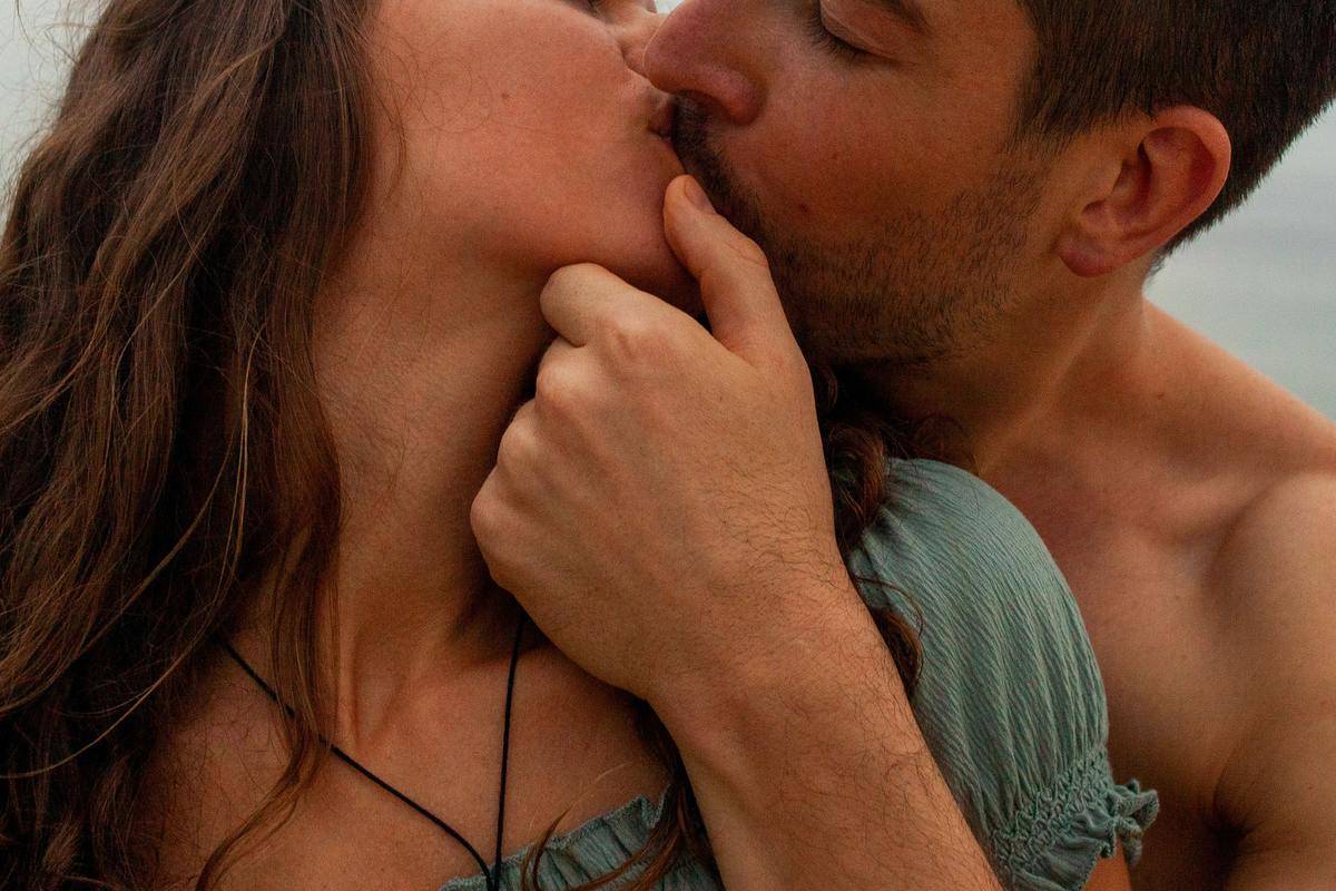 A man and a woman kissing, the man holding the woman's chin.