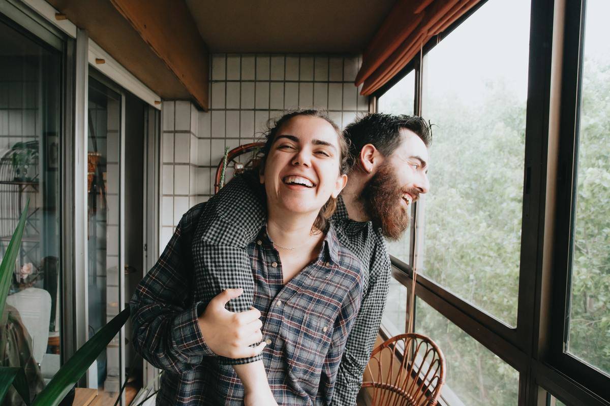 A couple laughing, the man embracing the woman from behind.