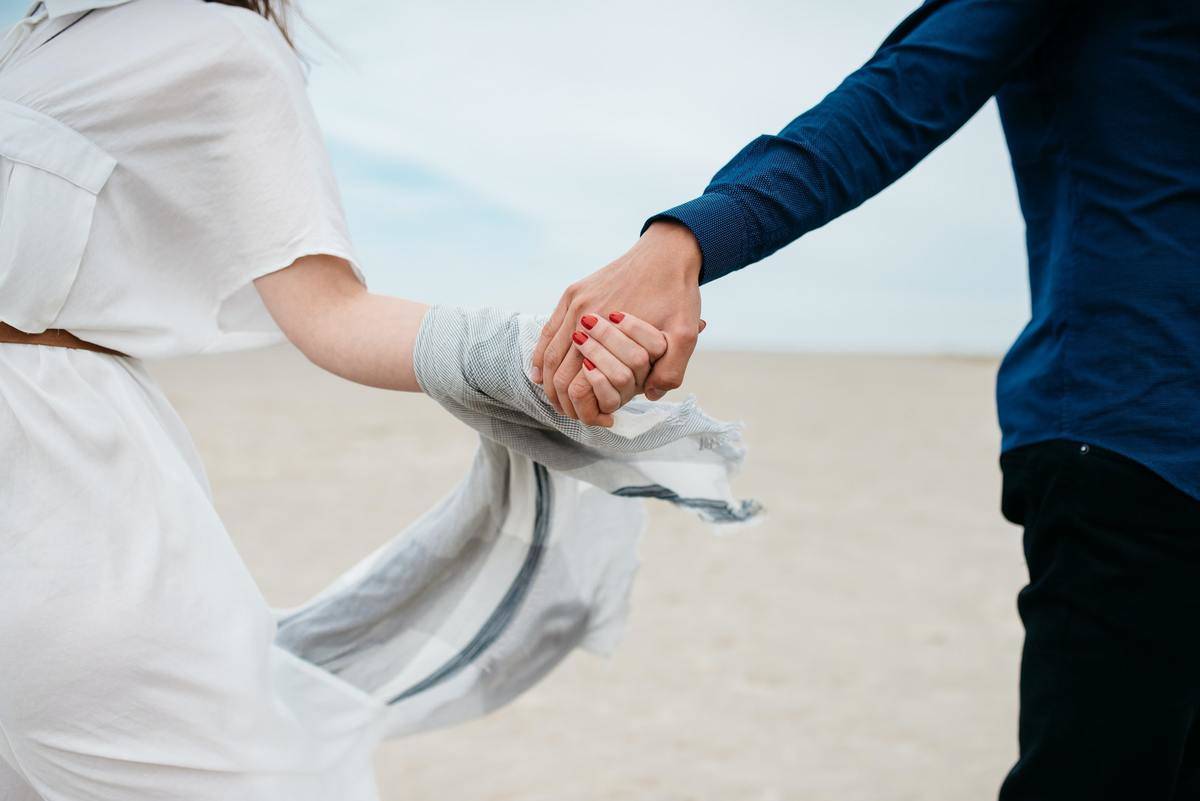 A couple holding hands on a beach.