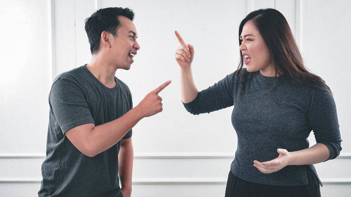 A man and a woman pointing fingers at each other while arguing.