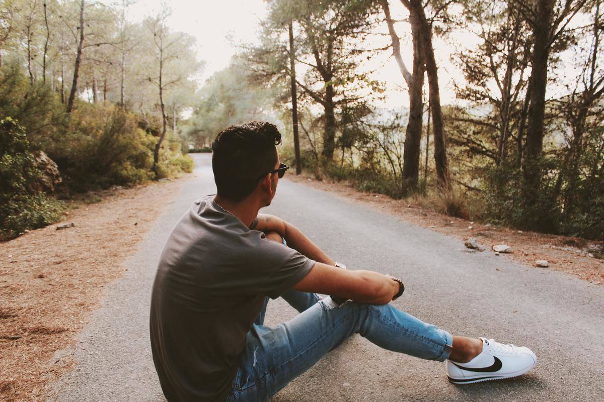 A man sitting on a road, looking forward.