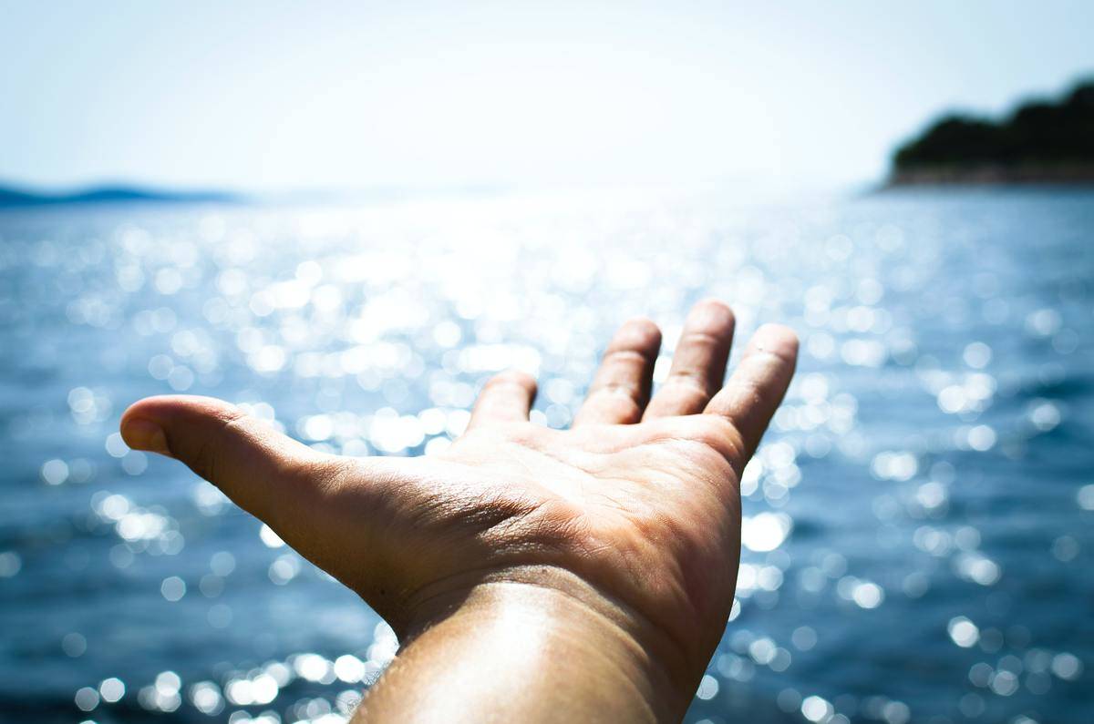 Person-hand-reaching-body-of-water