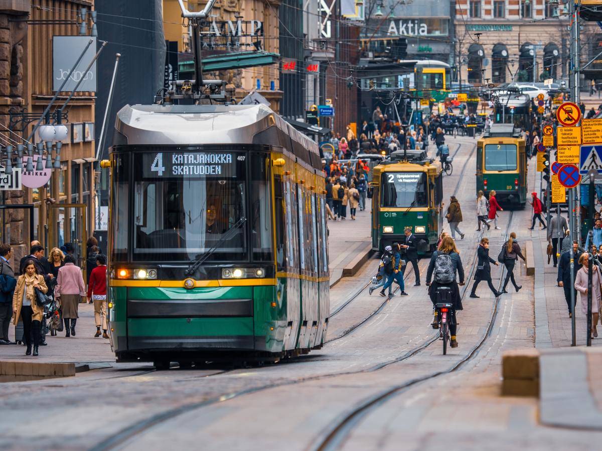 A busy street in Helsinki, including street cars driving down the road.