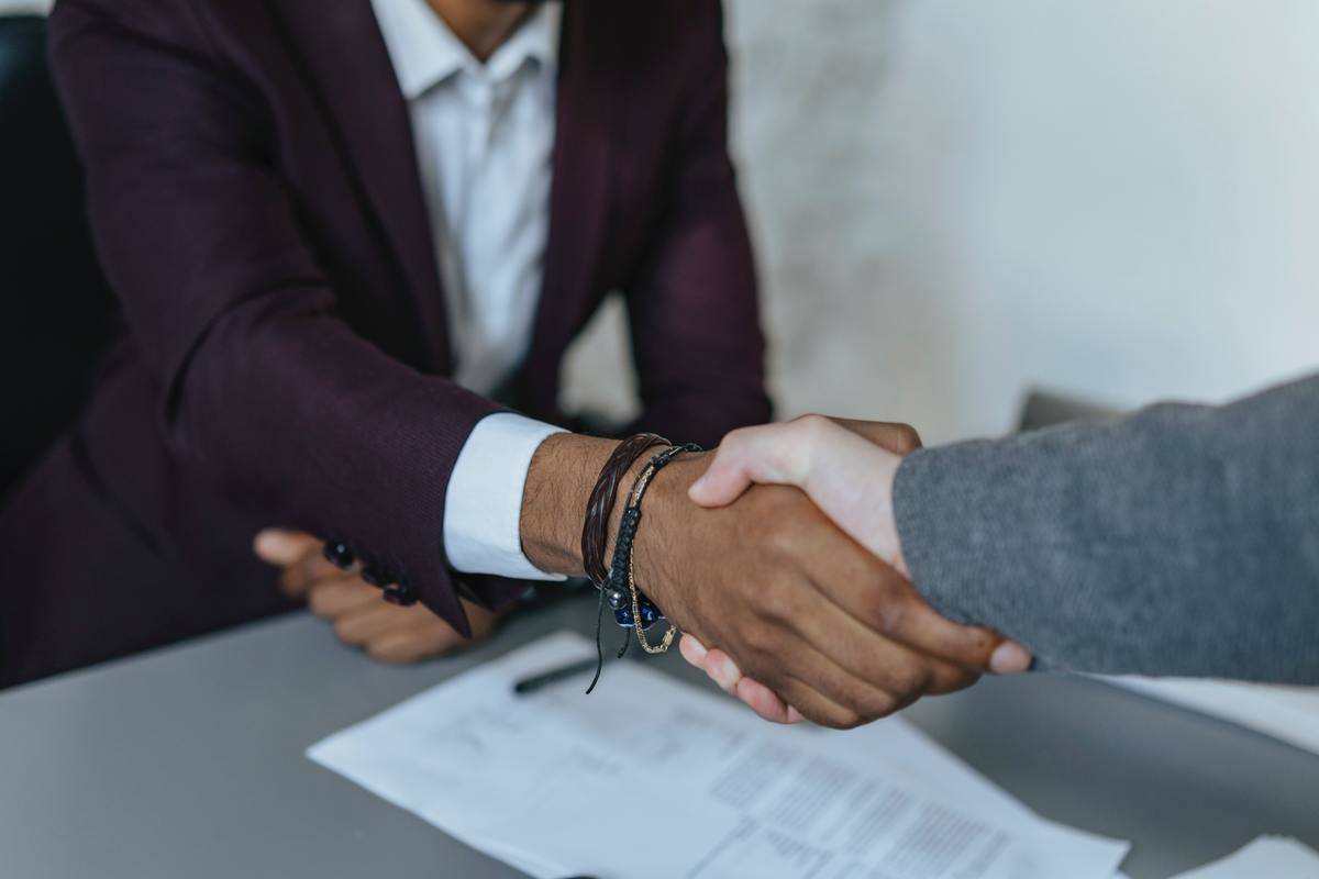 Two people shaking hands at what appears to be a job interview.