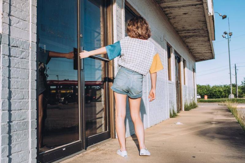 A girl about to open a door to a business.
