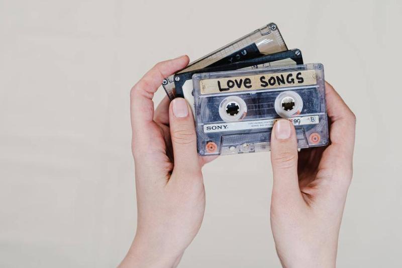 Someone holding three cassette tapes, one with a label that reads 'love songs'.