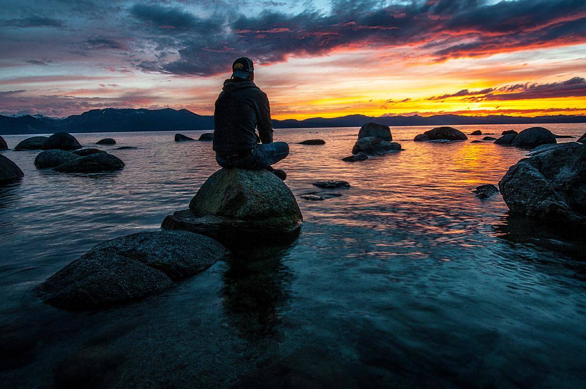 person-sitting-on-rock-on-body-of-water