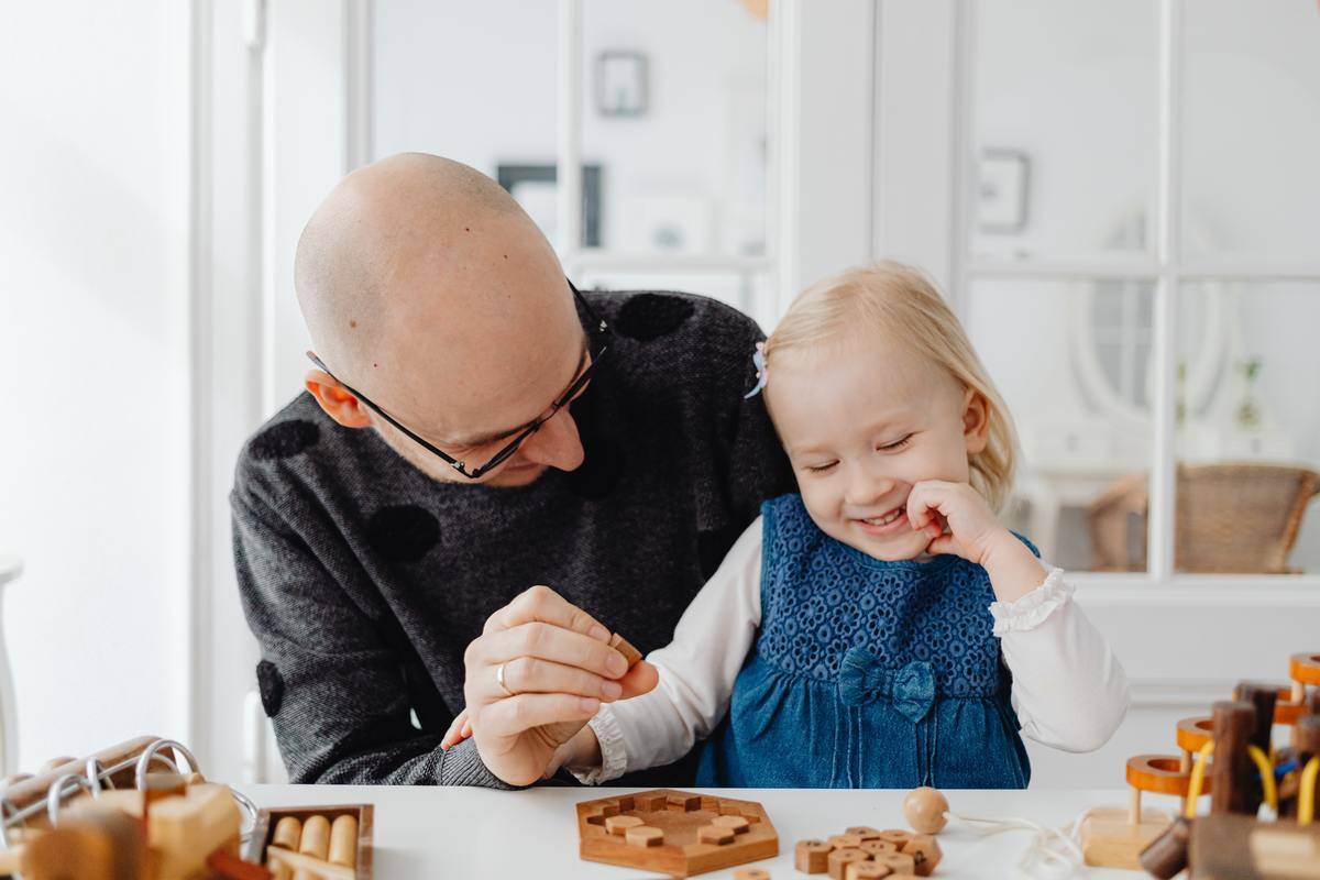 A man playing a puzzle with his daughter.