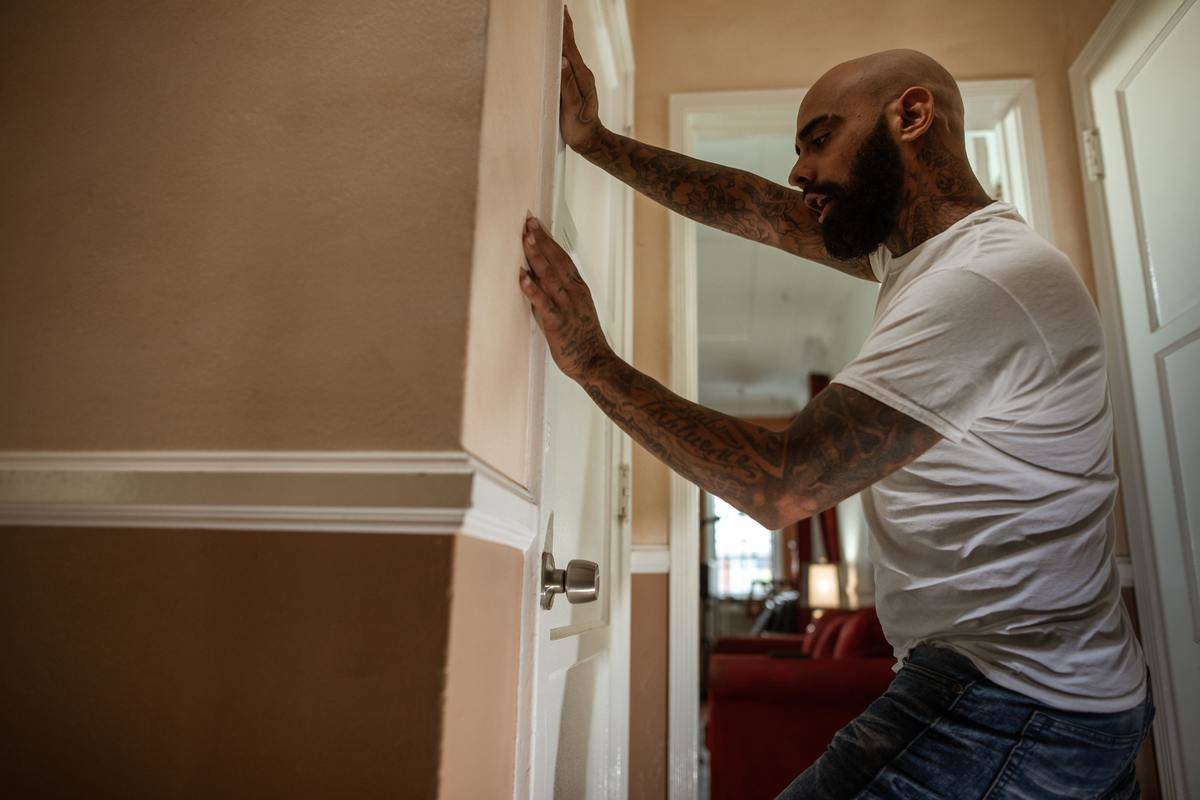 A man pushing against a door as he's speaking.