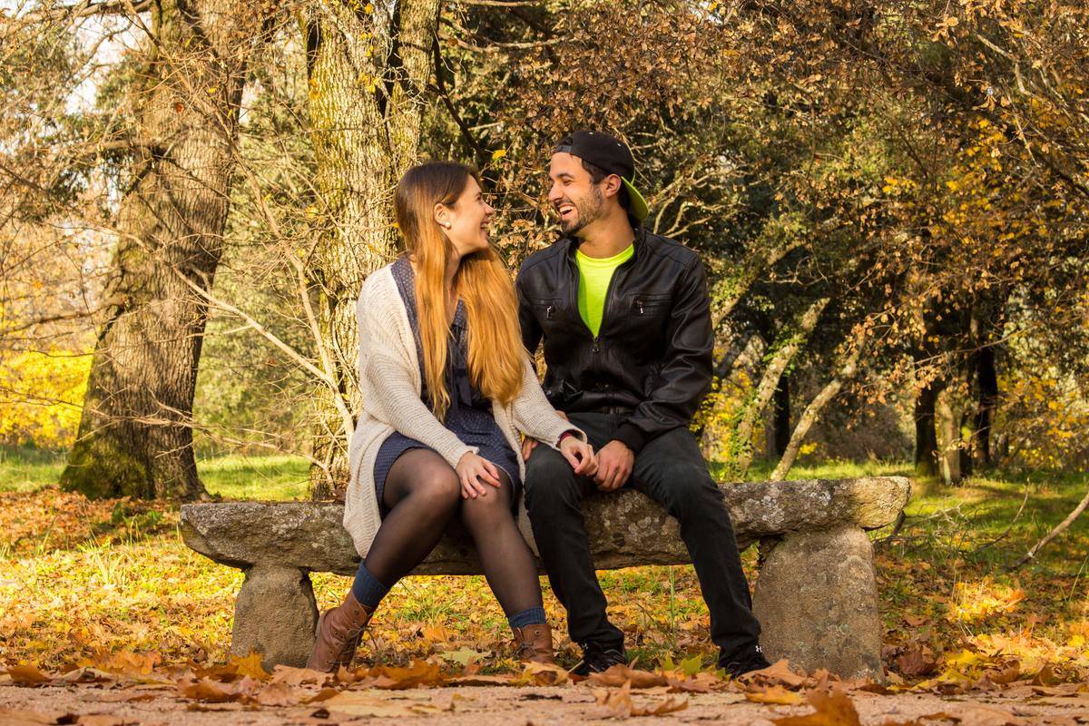 Two people sitting on a bench, laughing.