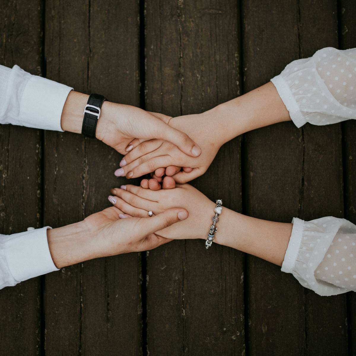 Two people holding hands across a wooden table.