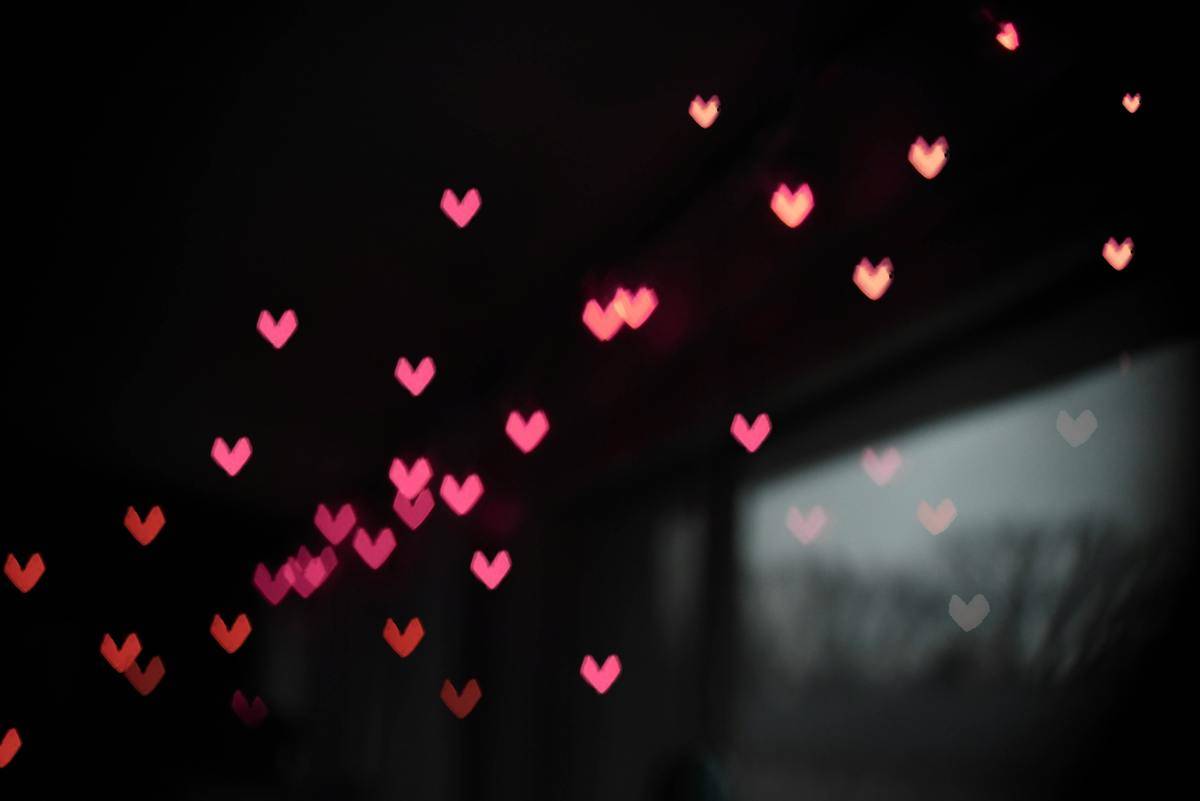 A dark room with a heart-shaped pink lighting effect scattering across it.