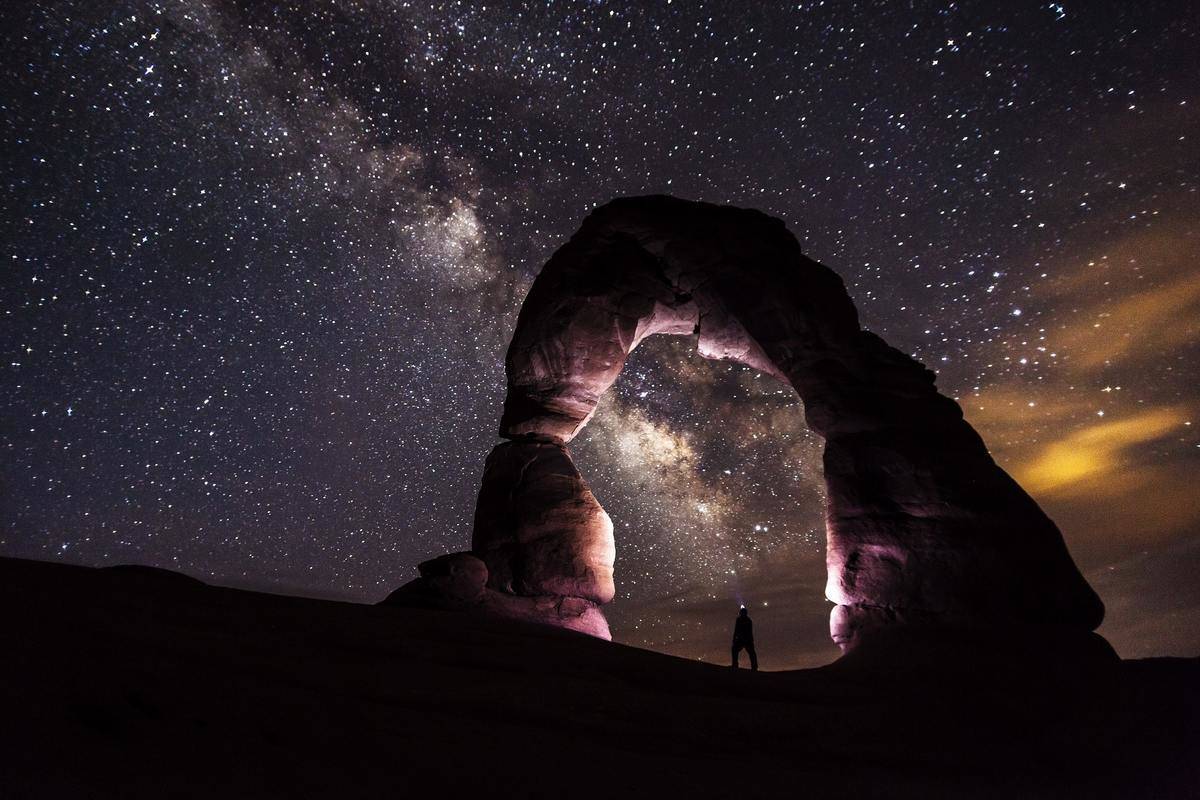 person-standing-under-a-rock-formation-on-a-starry-night