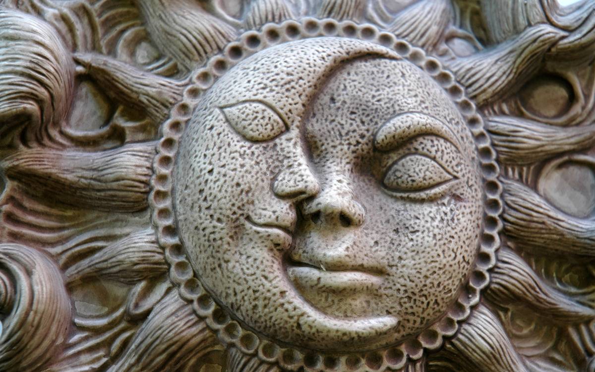 A sun and moon face design carved out of stone.