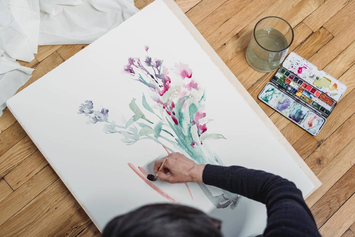 Someone painting a bouquet of flowers with watercolor paints.