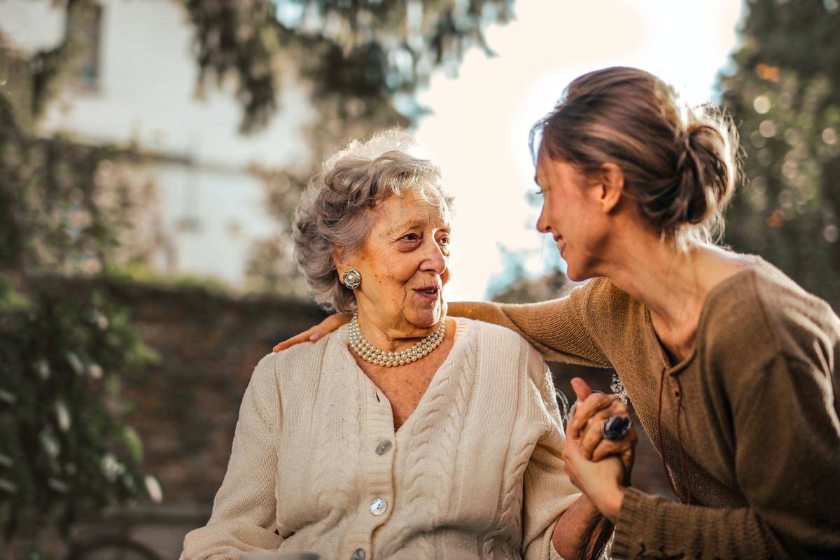 oyful-adult-daughter-greeting-happy-surprised-senior-mother-in-garden-