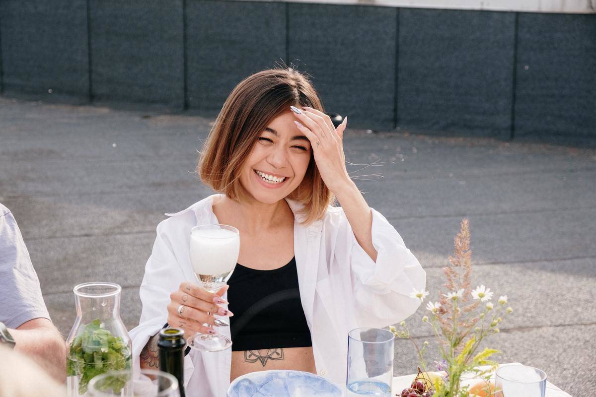 /woman-in-white-long-sleeve-shirt-holding-clear-drinking-glass