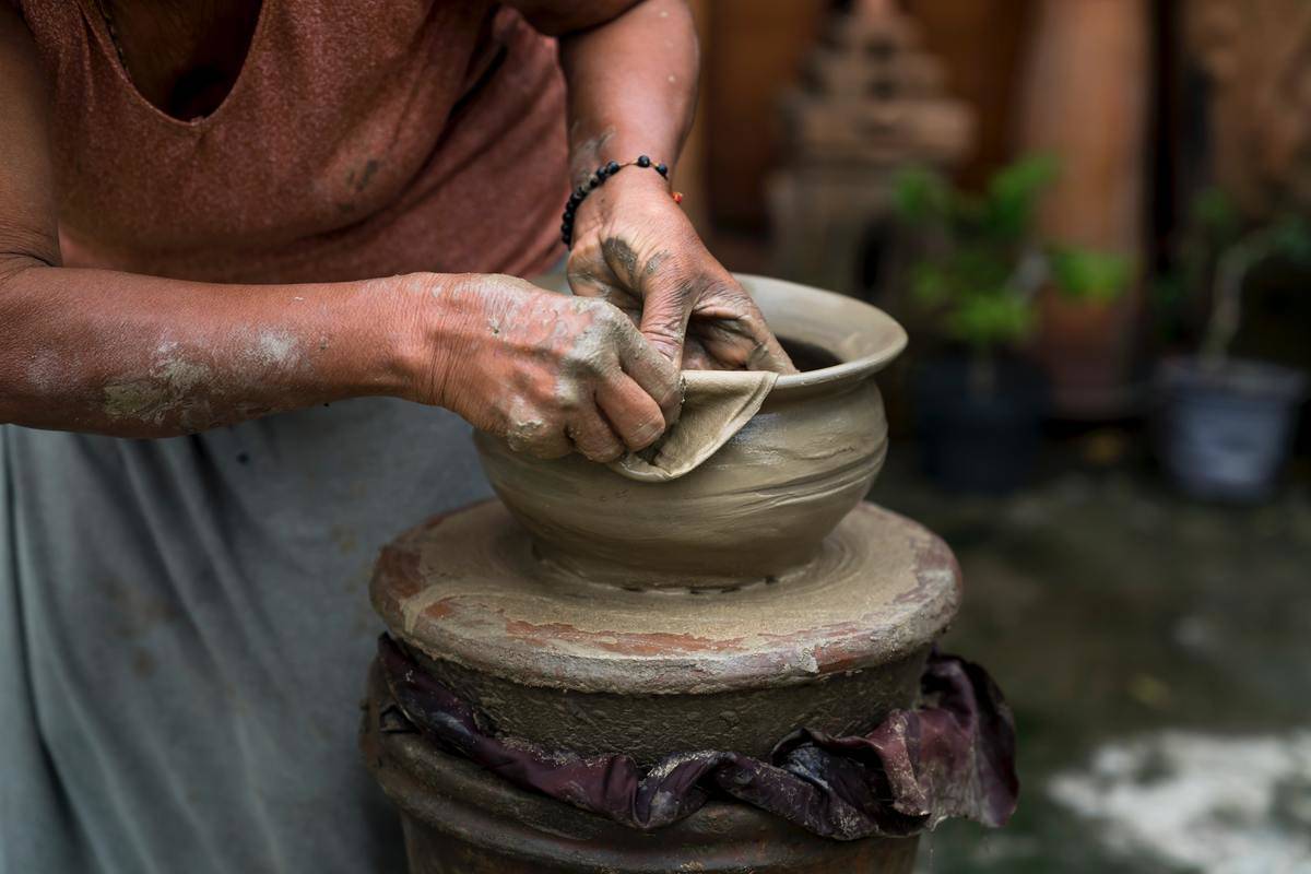 A closeup of someone sculpting a clay pot.