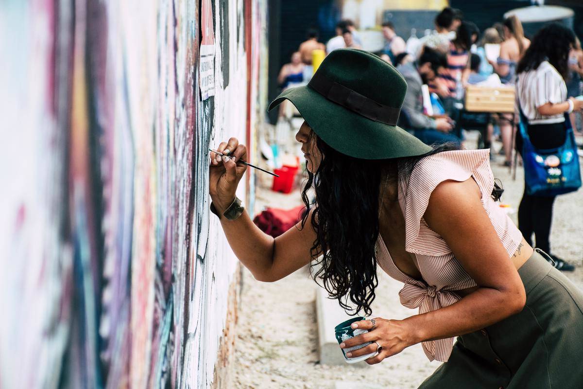 A woman leaning over as she paints on a wall.