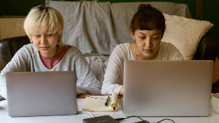 Two women sitting at laptops, working.