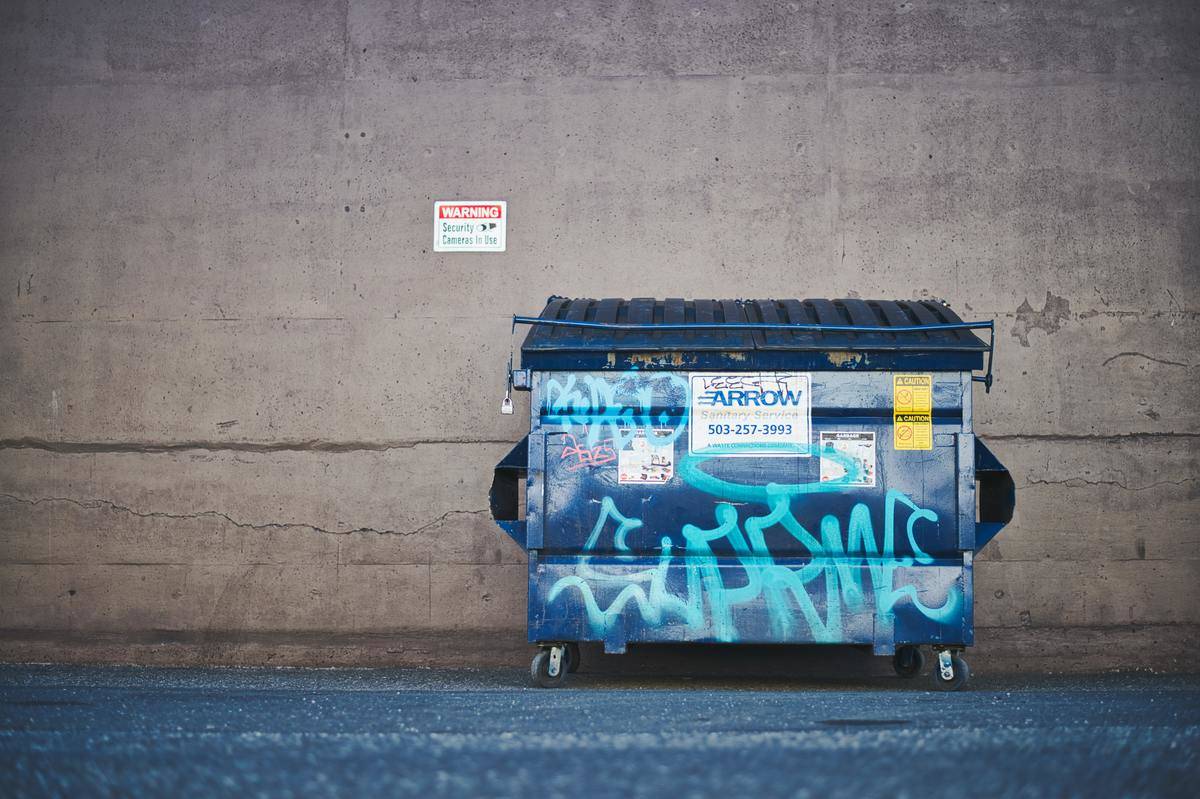A dumpster with graffiti on it in an alley.