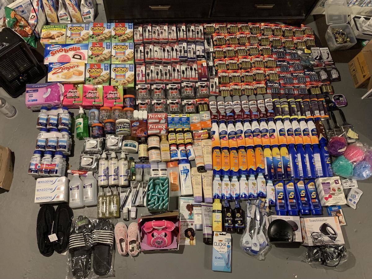 A very large haul laid out on someone's floor that includes tons of batteries, sunscreen, granola bars, and other household items.