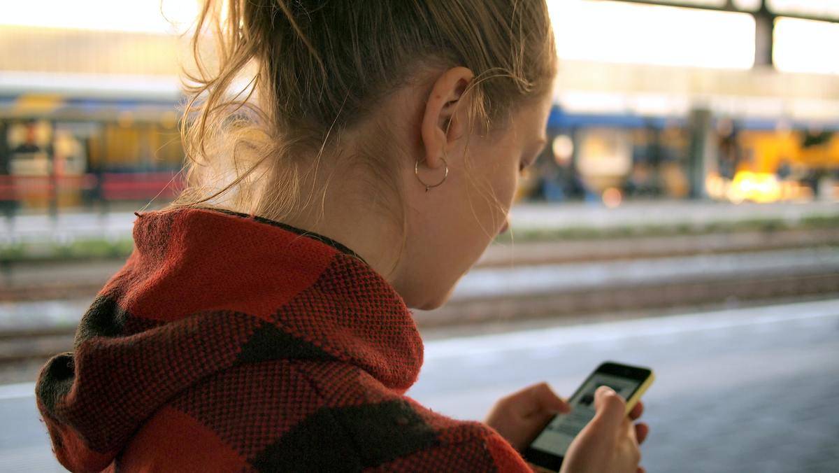 A girl looking down at her phone in her hands.