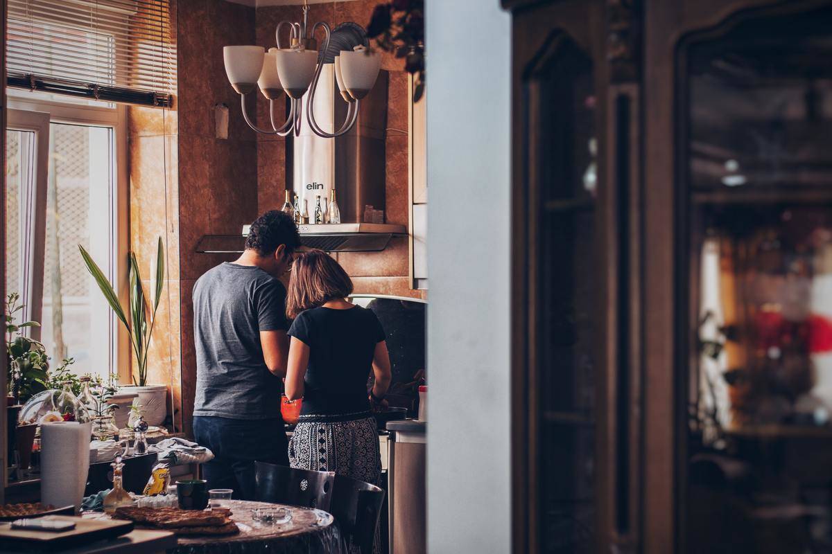 couple cooking together in their home, backs to the camera.